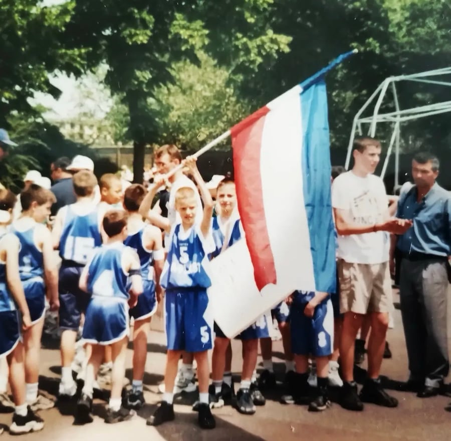 Coach Stefan Stankovic carrying a flag alongside his youth basketball team