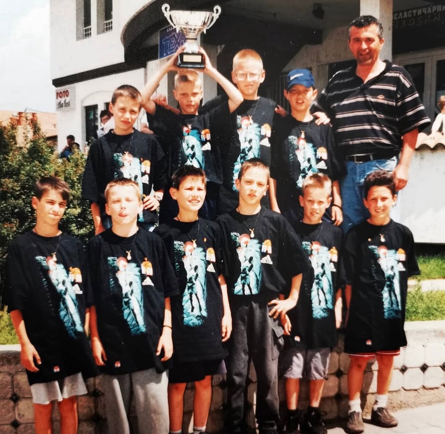Coach Stefan Stankovic with his youth basketball team holding a trophy