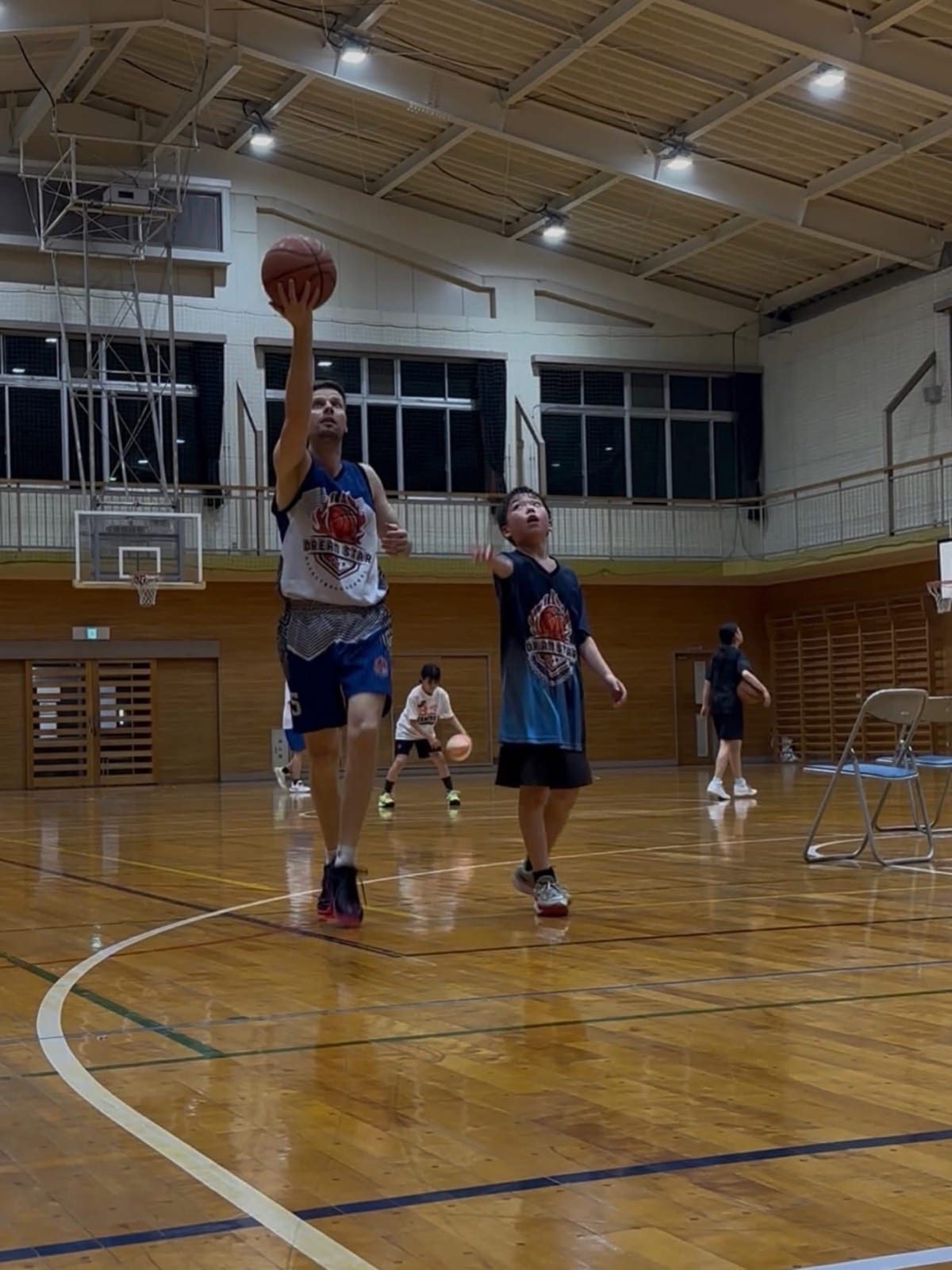 Coach Stefan Stankovic driving to the basket alongside a young player