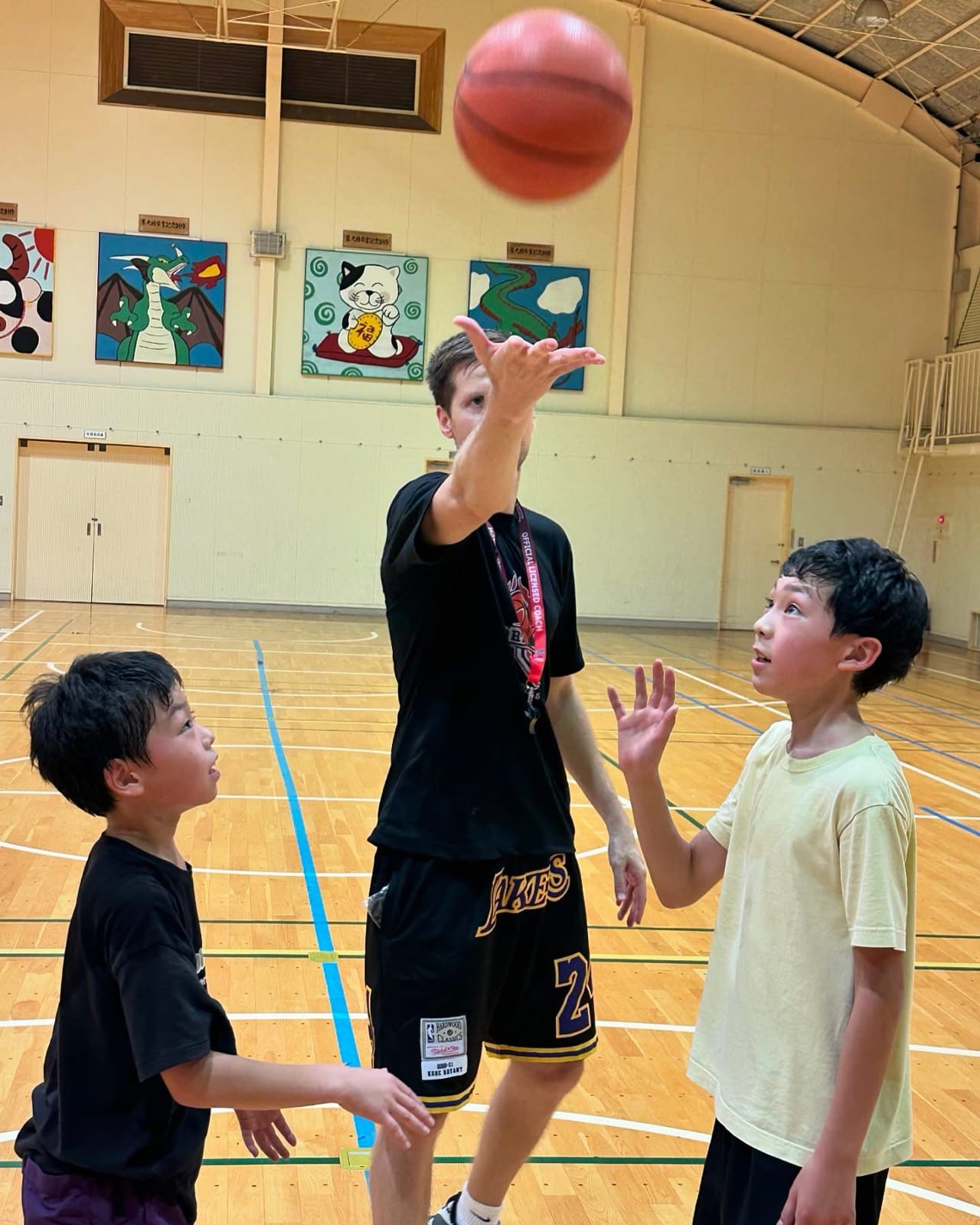 Coach Stefan Stankovic passing a basketball to two young players