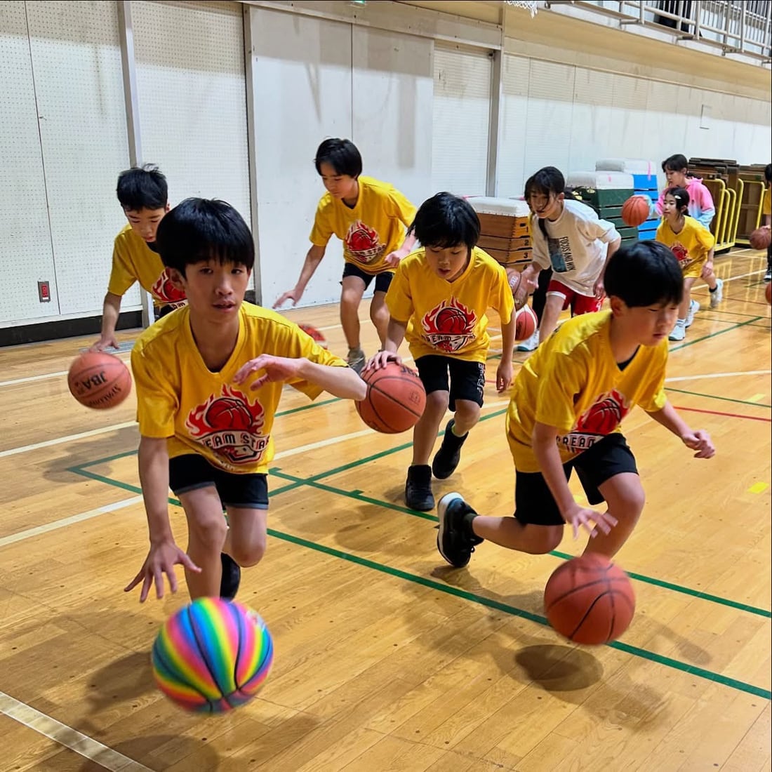 Young players dribbling basketballs during a team drill