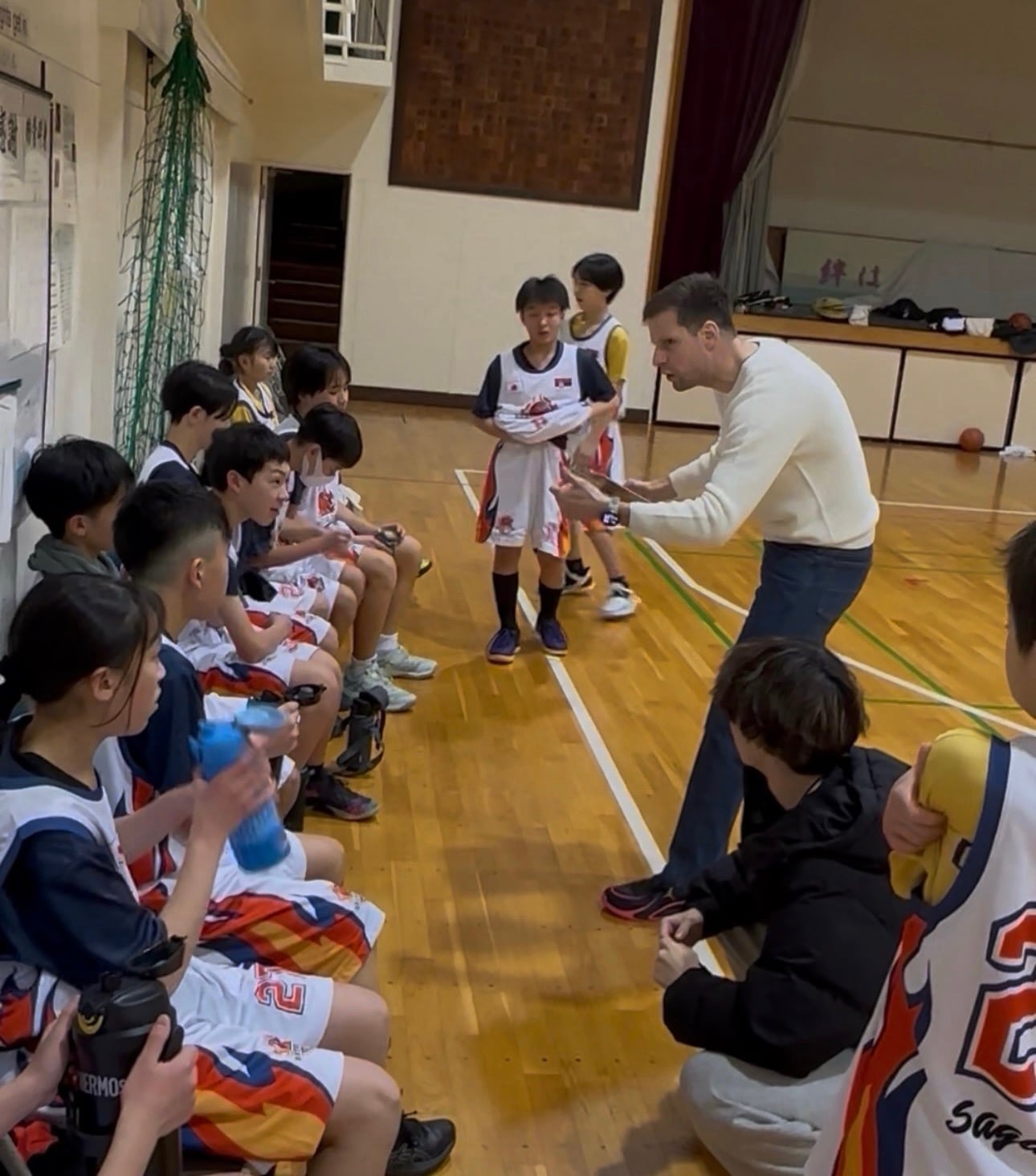 Coach Stefan Stankovic speaking with seated players during a break